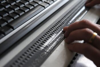 Finger ertasten die erhabenen Stifte auf einer Braillezeile